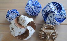 four different types of paper flowers on a wooden table with white and blue designs around them