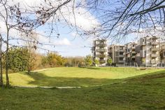 an apartment building in the middle of a grassy area with trees and grass on both sides