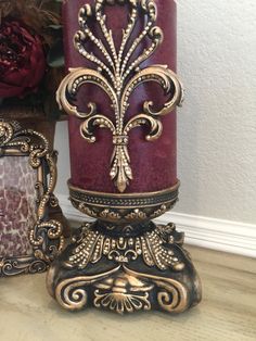 a decorative candle sits next to two ornate frames