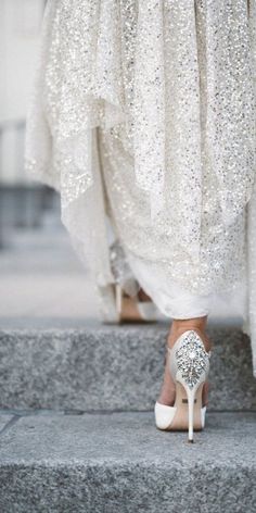 a woman in high heels standing on steps with her dress flowing down the bottom half