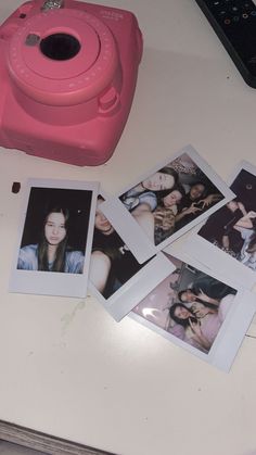 several polaroid photos are placed on a table next to a pink camera and remote control