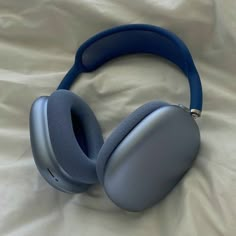 a pair of blue headphones laying on top of a white sheeted bed spread