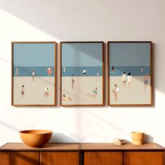 three framed pictures hang on the wall above a dresser with a bowl in front of it