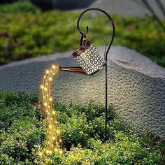 a light up watering can in the middle of some grass with lights coming out of it