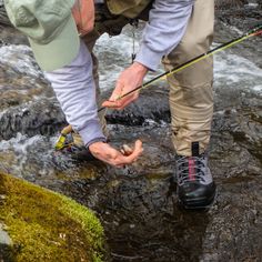 a man standing on top of a river while holding onto a fishing pole and hook