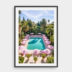 an aerial view of a swimming pool with umbrellas and palm trees in the background