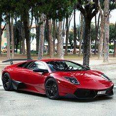 a red sports car parked in front of some trees