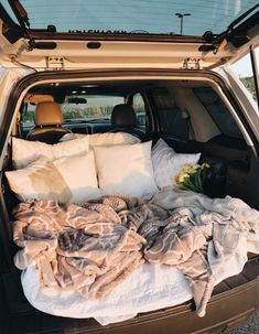 the back end of a car with blankets and pillows in it's trunk area