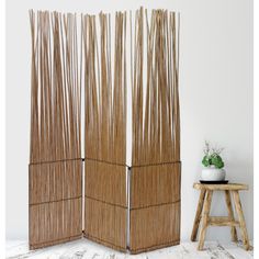 two tall bamboo screens sitting on top of a wooden floor next to a planter