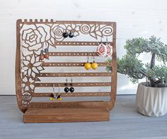 a wooden display with earrings on it next to a potted plant