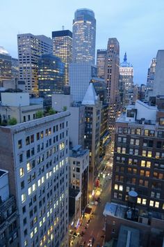 the city is lit up at night with many tall buildings in the foreground and cars on the street below