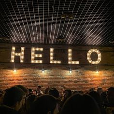 a group of people standing in front of a brick wall with the word hello on it