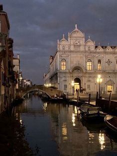 boats are parked along the side of a canal at night