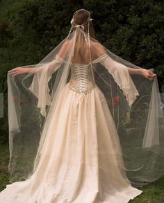 a woman in a wedding dress with a veil on her head and arms outstretched to the side