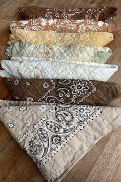 six bandanas laid out on a wooden floor in different colors and patterns, all lined up together