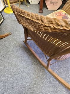 a wicker rocking chair sitting on top of a carpeted floor next to pictures