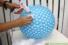 a person using glue to decorate a blue and white polka dot paper ball ornament