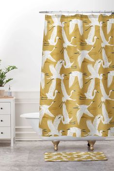 a shower curtain with birds on it in a white and yellow bathroom, next to a bathtub