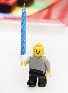 a lego man holding a lit candle in his hand