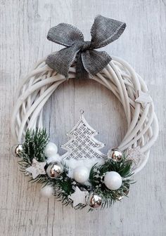 a white wreath with silver ornaments and a christmas tree ornament