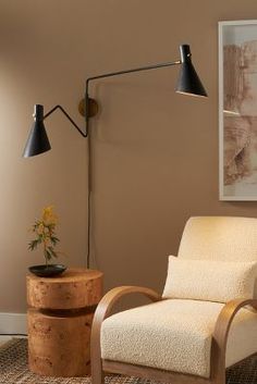 a living room with a chair, lamp and painting on the wall in it's corner