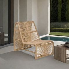 a wicker lounge chair next to a swimming pool with an ottoman and coffee table