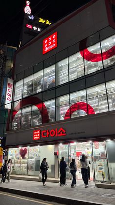 people are walking in front of a building with red and white numbers on the side