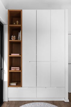 an empty room with white cupboards and wooden shelves on the wall next to a round rug