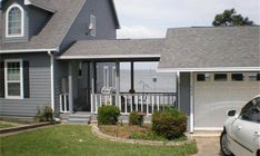 a car is parked in front of a house with a gray roof and white trim