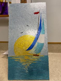 a sailboat on the water is depicted in this mosaic tile art piece, which features blue and yellow colors