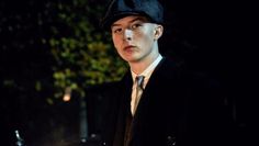 a young man in a suit and tie standing outside at night with a lit candle