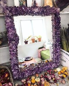 a purple mirror sitting on top of a table next to flowers and baskets filled with plants