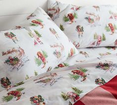 a bed covered in white and red sheets with santa claus on it's sleigh