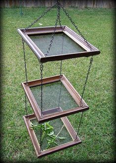 three tiered glass planter with metal chains hanging from it's sides in the grass