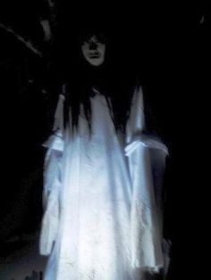 a ghostly woman standing in the dark