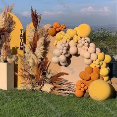 an outdoor display with yellow and orange balloons on the grass, surrounded by tall grasses