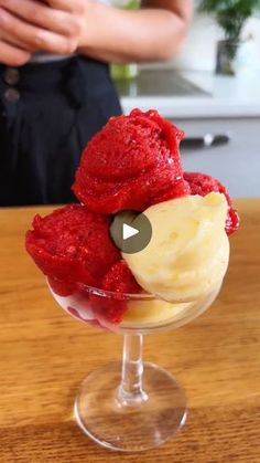 a person standing in front of a wooden table with a bowl of ice cream and two scoops of fruit