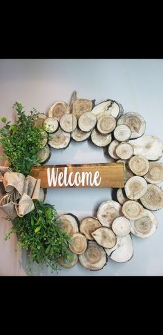 a wreath made out of logs with the word welcome hanging on it's side