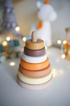 a stack of wooden rings sitting on top of a white table next to christmas lights