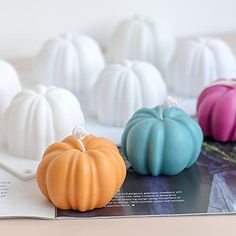 four small pumpkins sitting on top of a table next to an open magazine with pages