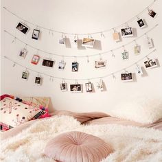 there is a bed with pictures hanging on the wall and pillows in front of it