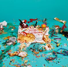 a birthday cake surrounded by confetti and sprinkles on a blue background