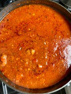 a pot filled with red sauce sitting on top of a stove