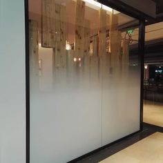 a glass wall in front of a building with lights hanging from it's sides