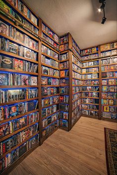 a room filled with lots of books next to a wall covered in shelves full of movies