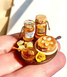 a miniature plate with honey and cookies on it in the palm of someone's hand