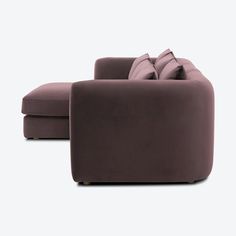 a purple couch sitting next to a chair on top of a white floor with pillows