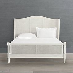 a white bed sitting on top of a hard wood floor next to a gray wall