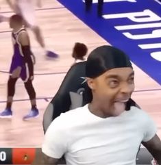 a man sitting on top of a chair in front of a basketball court