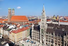 an aerial view of a city with tall buildings and red roof tops in the foreground